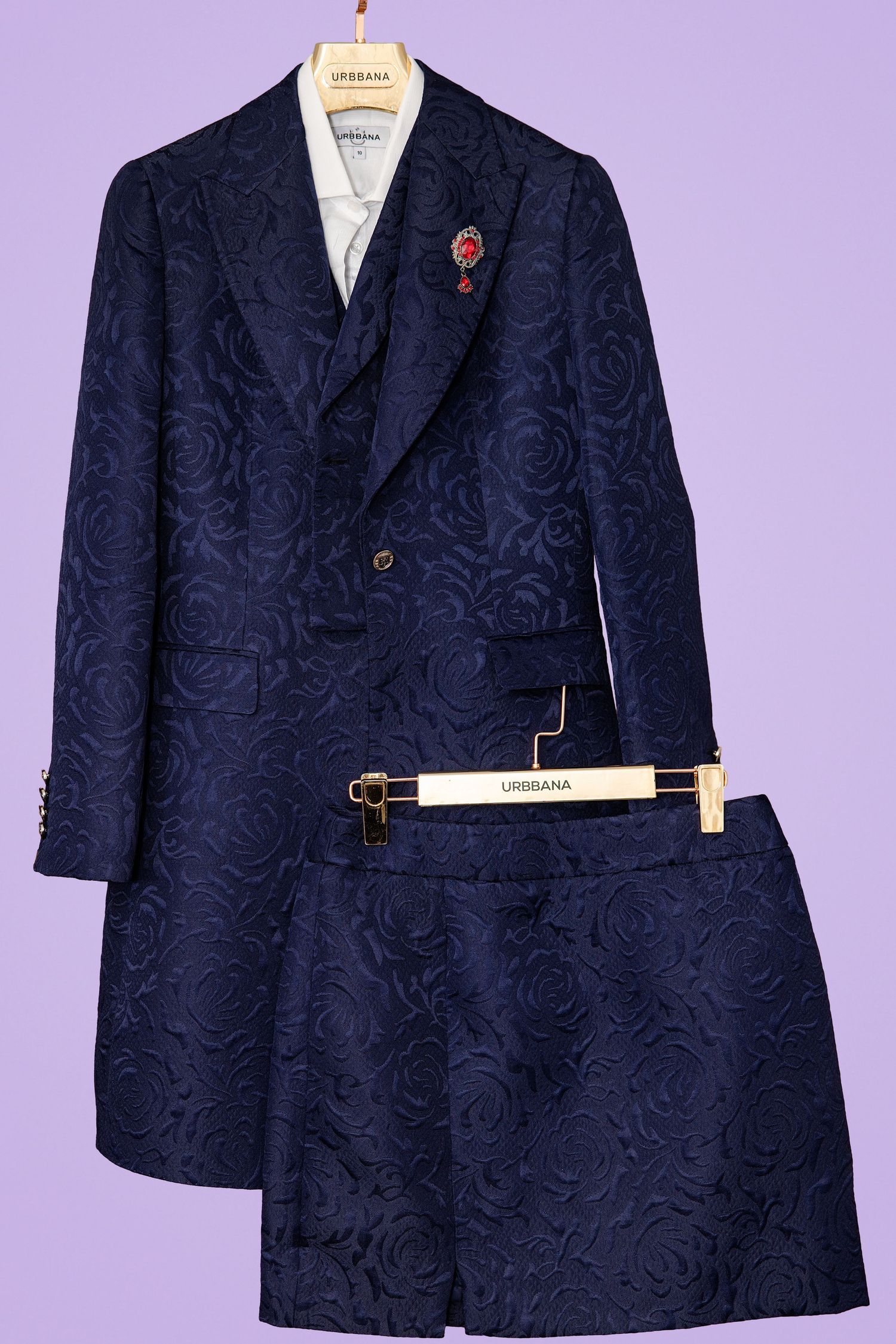 Navy blue floral jacquard double-breasted blazer and mini skirt suit set displayed on hangers against purple background.