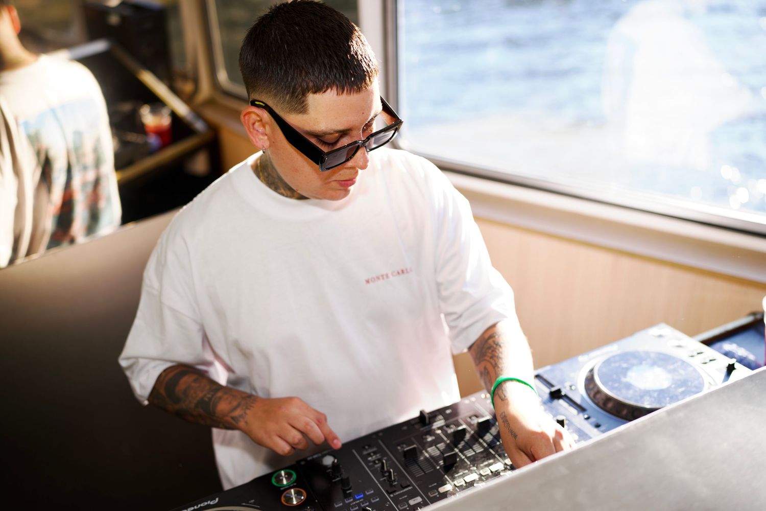 DJ wearing sunglasses focused on mixing tracks on the DJ controller.