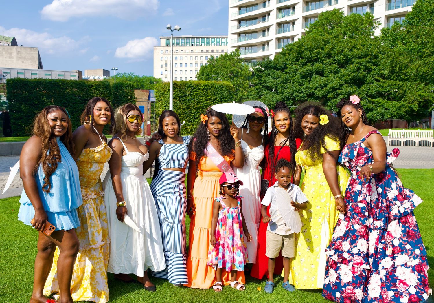 Group of women wearing colorful formal dresses posing outdoors on lawn by ARIETA Studios.