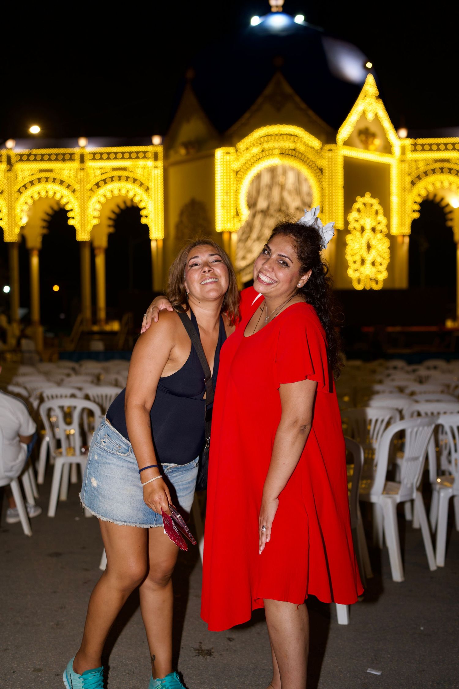 Two women embracing under fair arches / Dos mujeres abrazándose bajo los arcos del Real.
