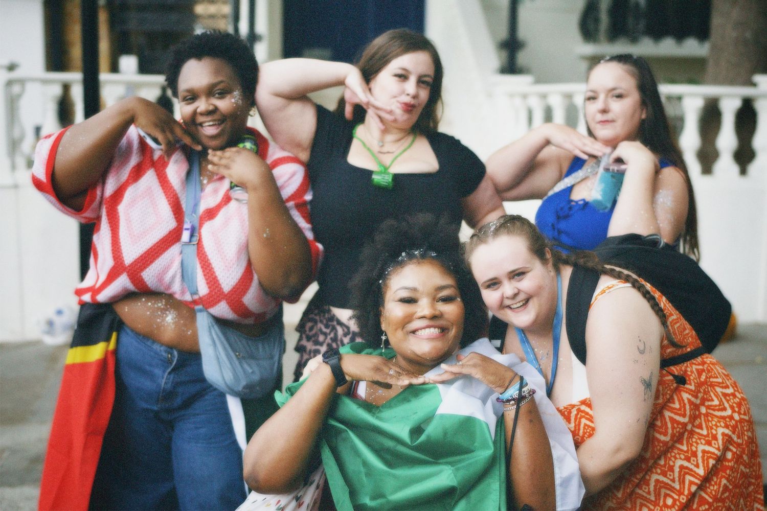 A diverse group of friends celebrating together with Nigerian and national flags on the road.