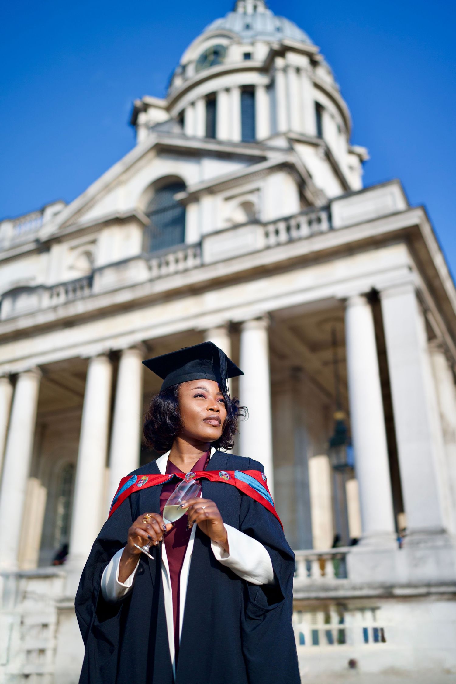 Full-length graduation portrait in front of historic Greenwich architecture by ARIETA Studios.
