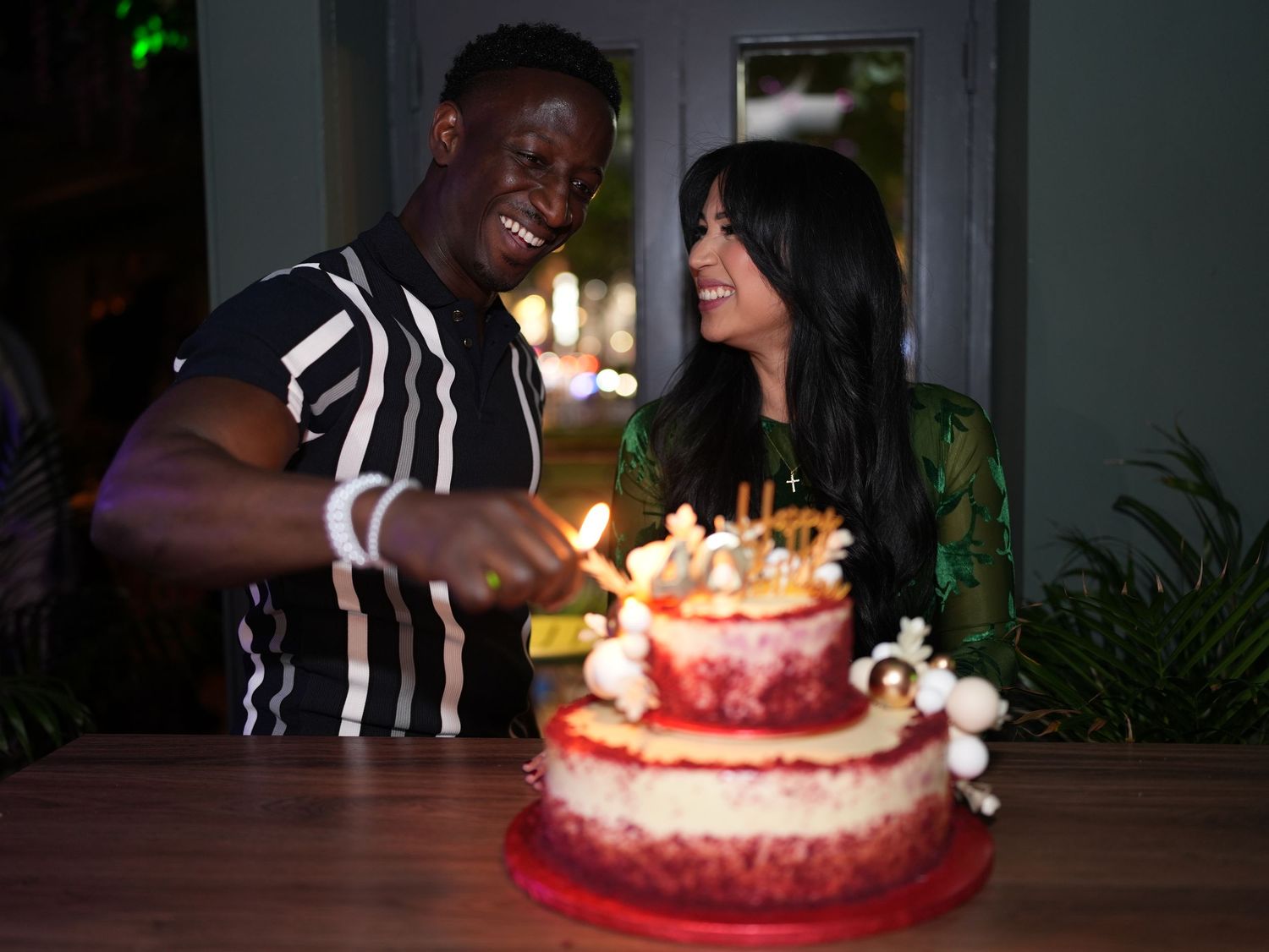 Candid of a Jaia lighting candles on a tiered cake while Rehana smiles in a green dress at her 40th birthday celebration.