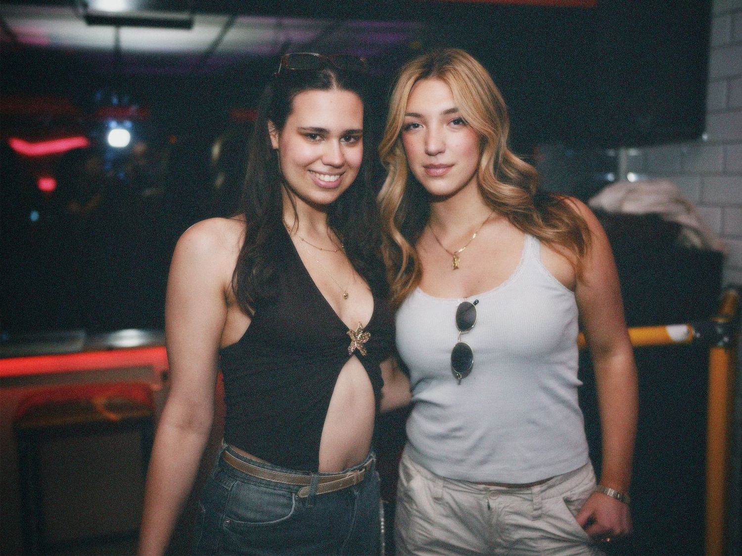 Two women posing together at indoor nightlife event captured by ARIETA Studios.
