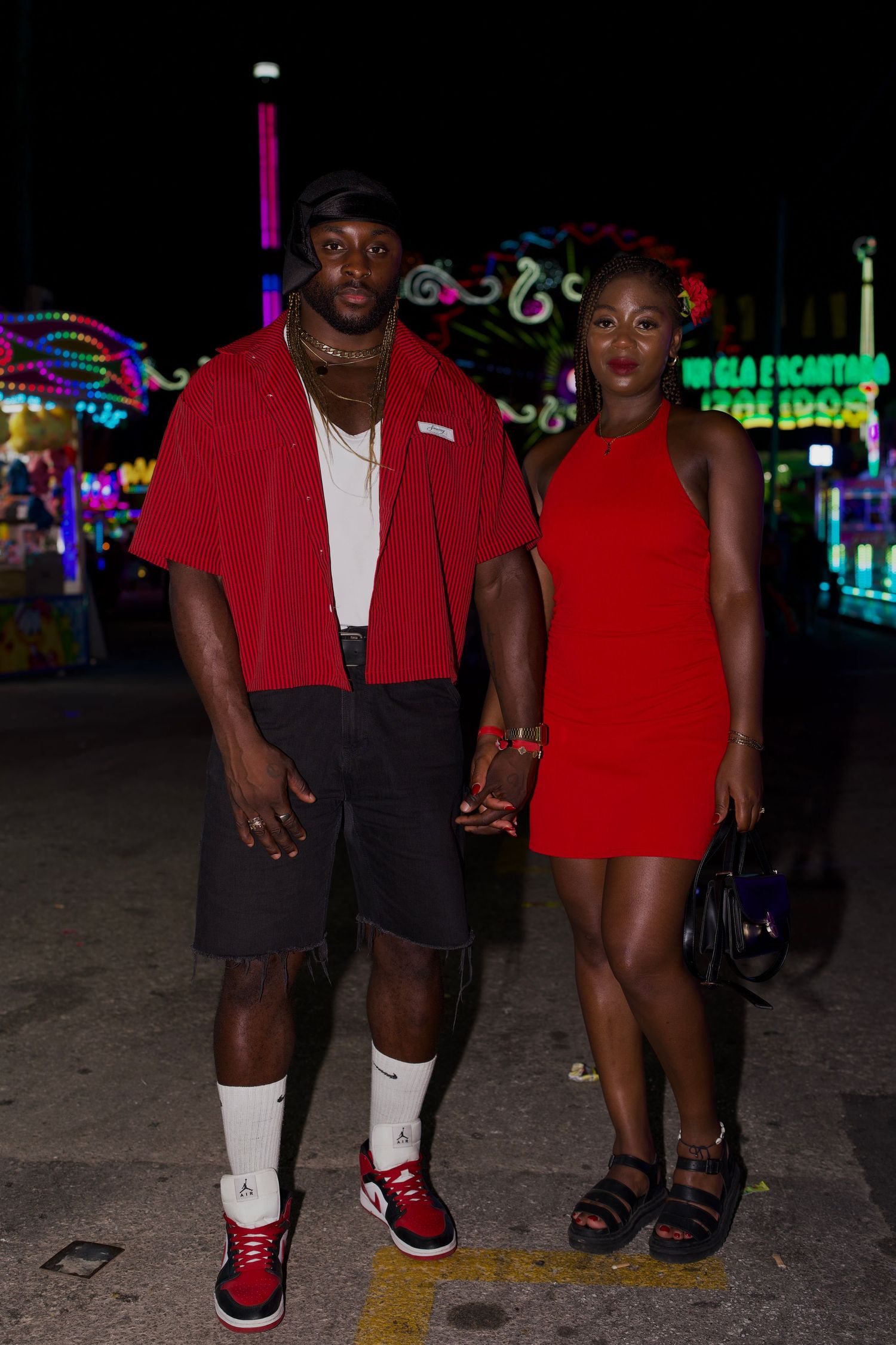 Stylish couple in red outfits at Feria de Málaga at night / Pareja estilosa vestida de rojo de noche en la Feria de Málaga