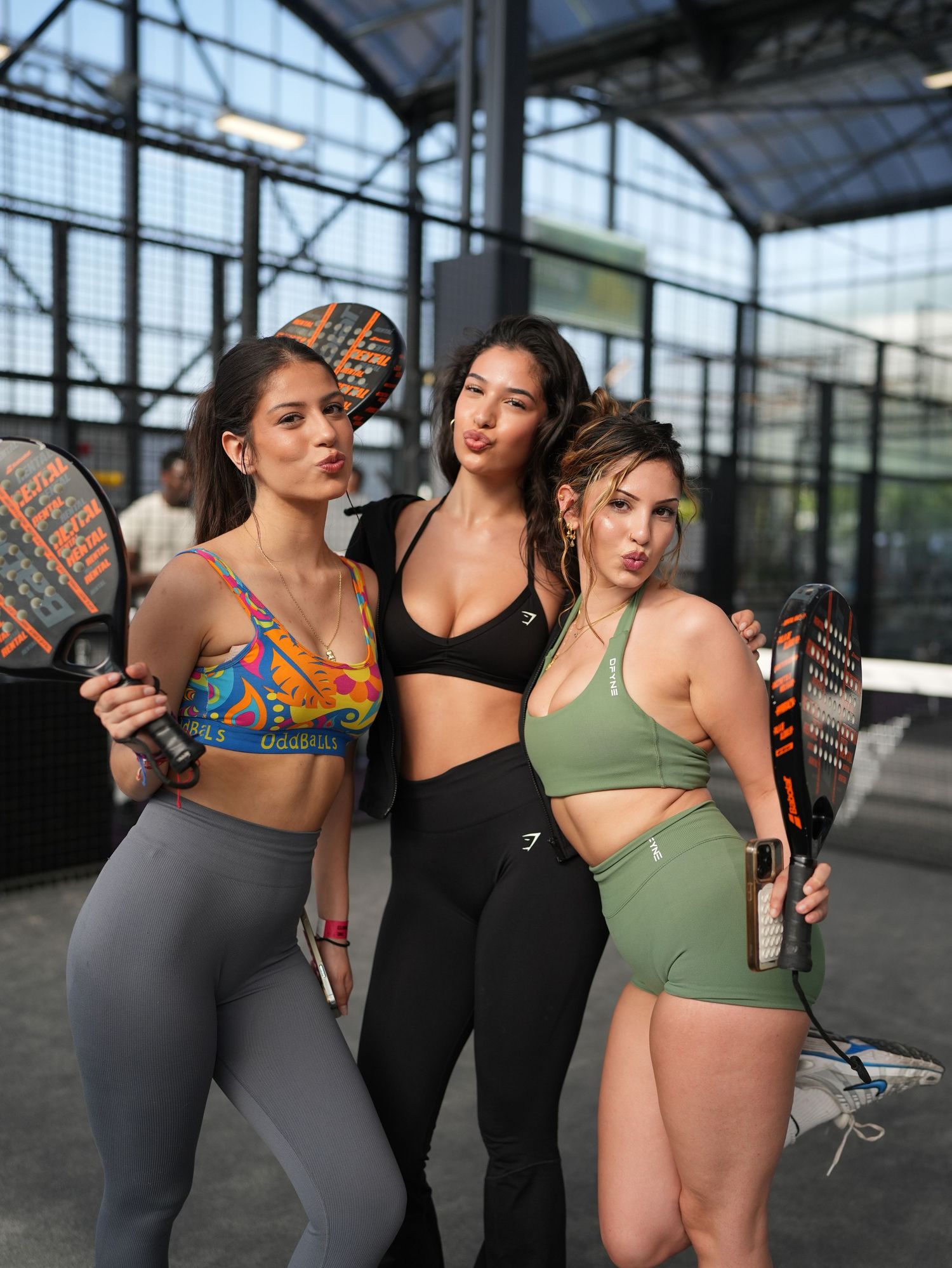 Three women in sportswear posing with padel rackets by ARIETA Studios.