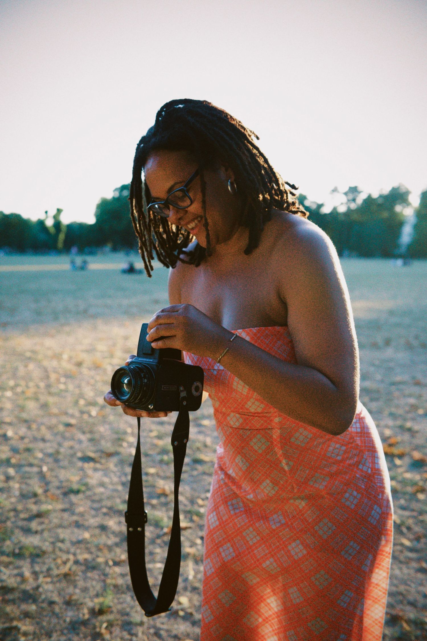 Photographer checking camera settings at outdoor summer event by ARIETA Studios.