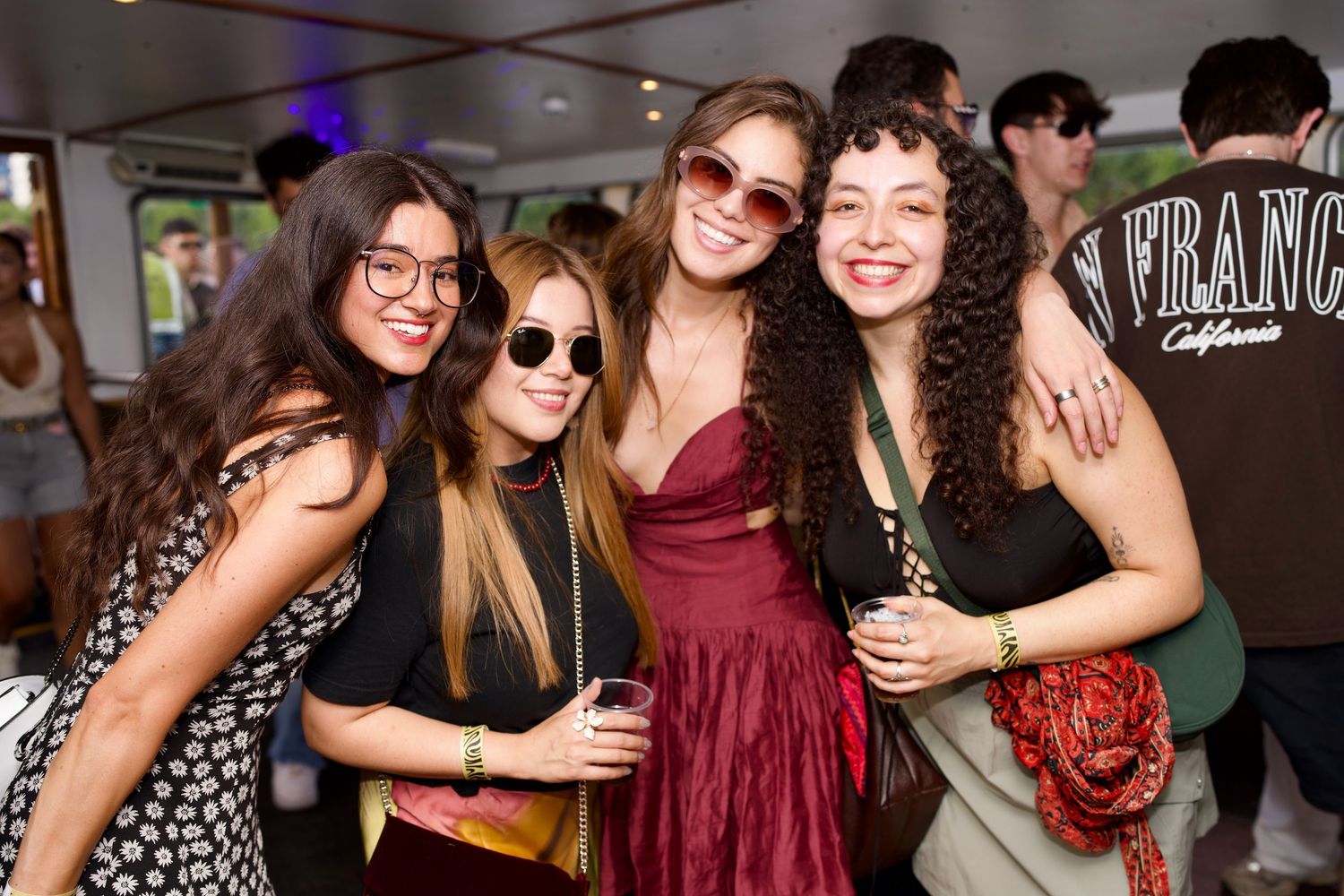 Group of four women smiling and posing together at On the Thames boat party by ARIETA Studios.