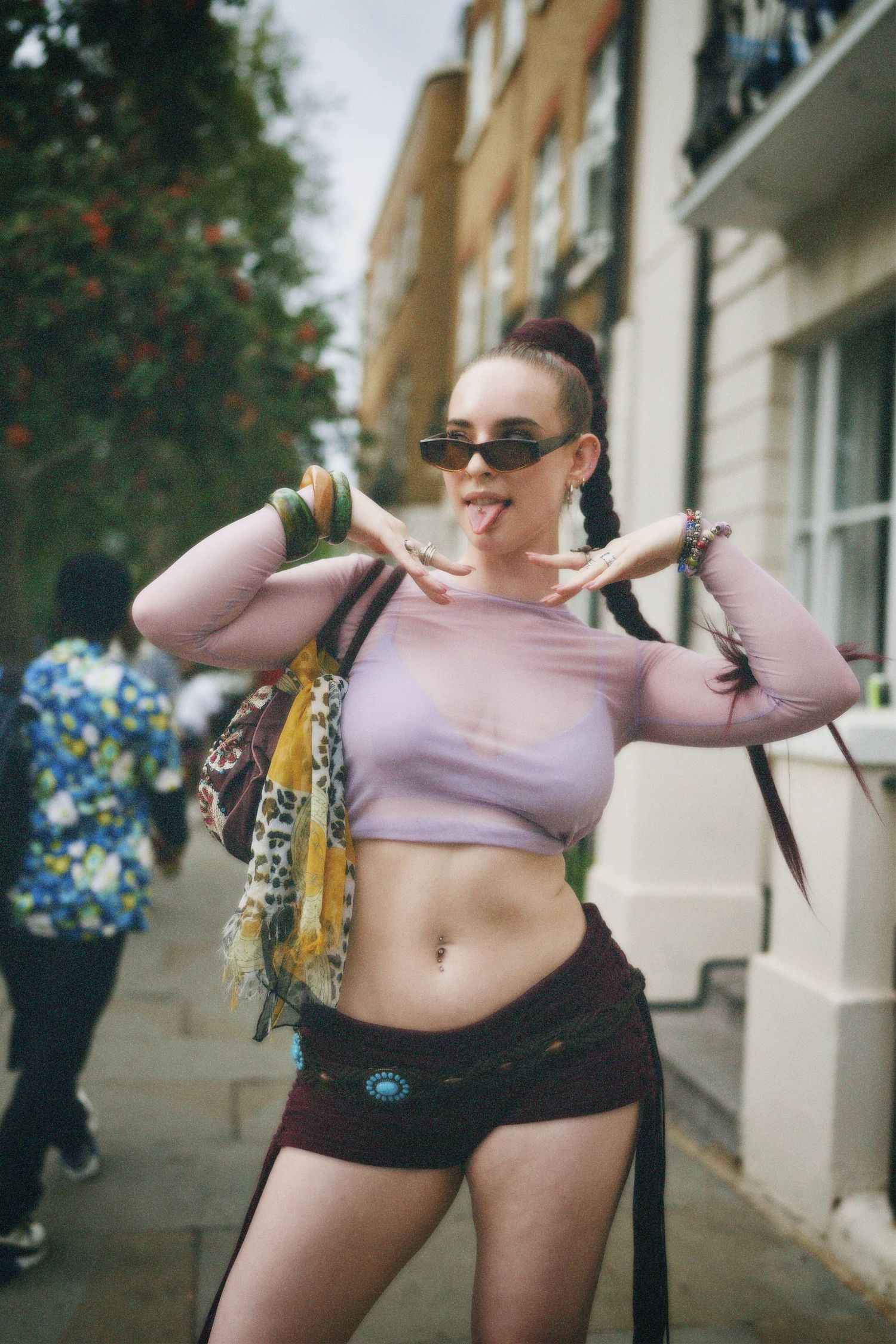 Street portrait of a woman striking a signature pose wearing a lilac crop top.