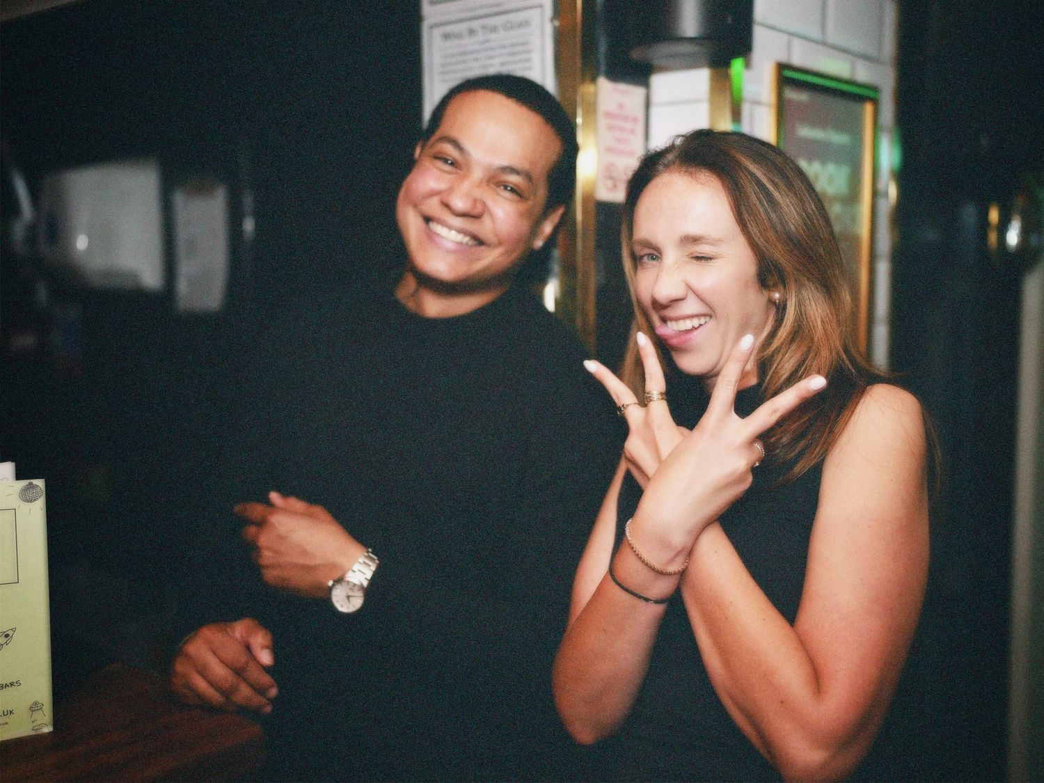 Man and woman smiling and making hand gestures at indoor venue event by ARIETA Studios.