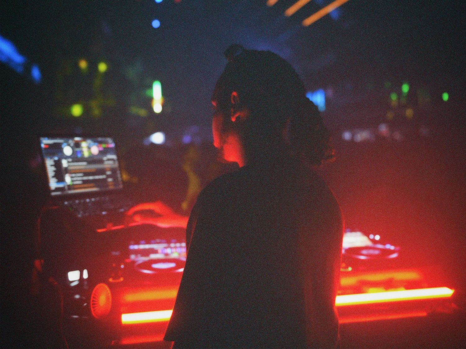 Silhouette of DJ performing behind lit decks at Paradise Super Club event by ARIETA Studios.