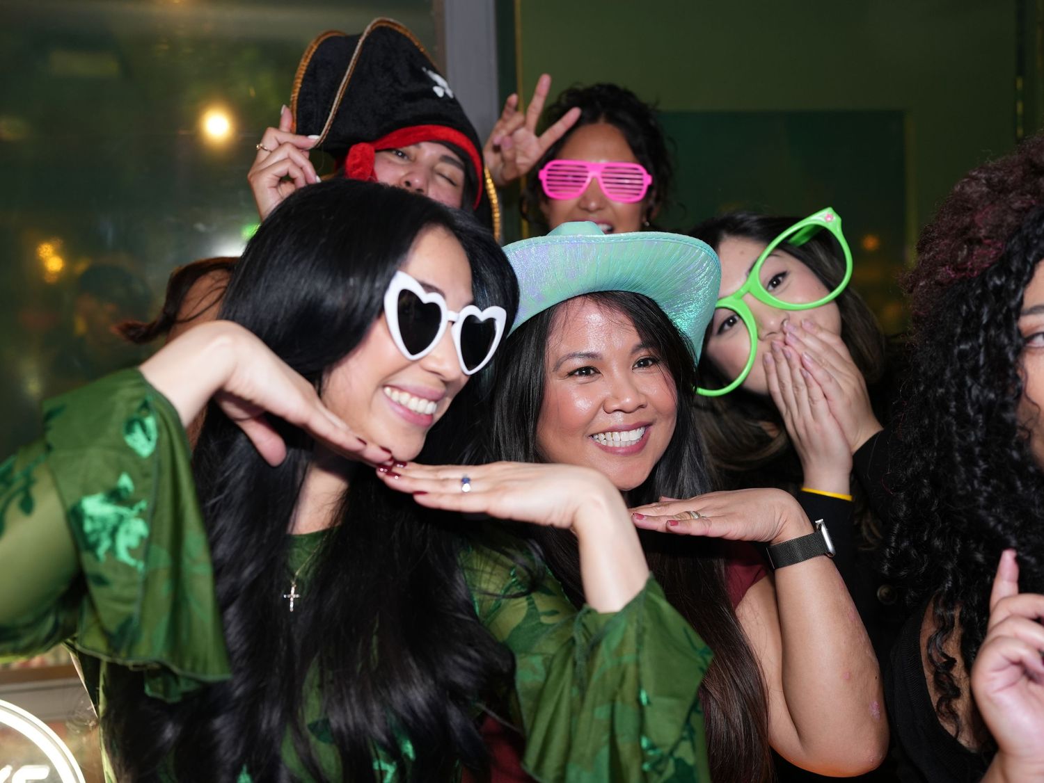 A group of friends playfully posing and laughing with party props in a photo booth style shot.