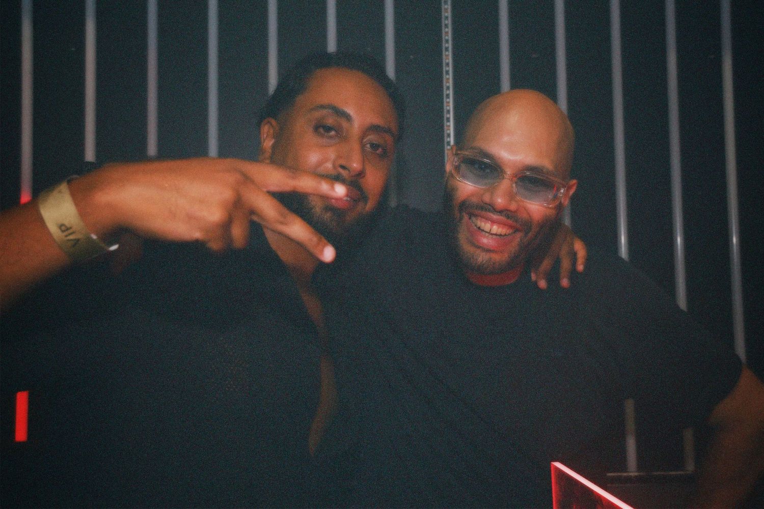Two friends posing together. / Dos amigos posando juntos bajo las luces del club.