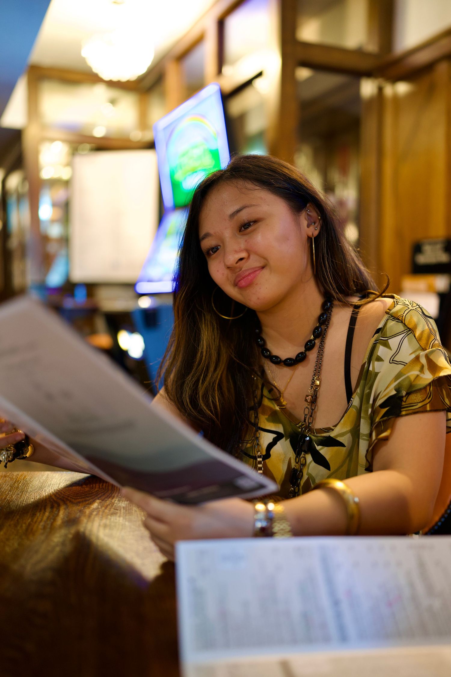 Teen girl smiling behind her Heathers show programme at the pub table.