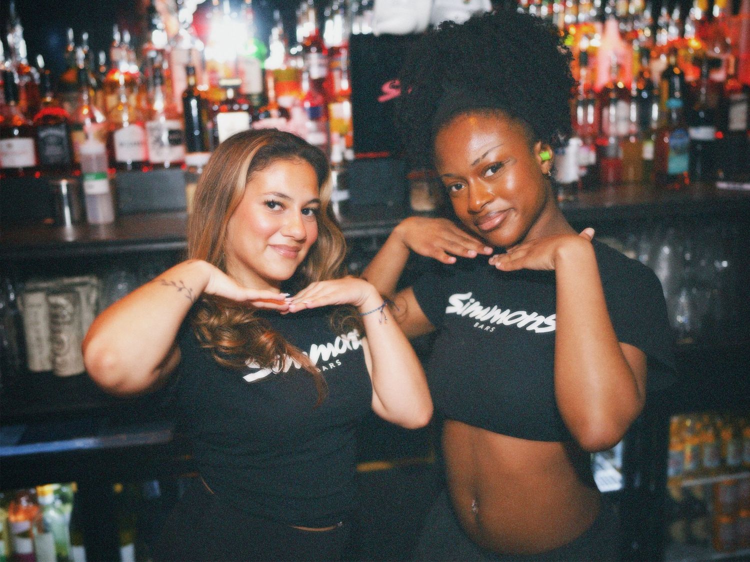 Two women posing behind bar counter at Simmons Leicester Square by ARIETA Studios.