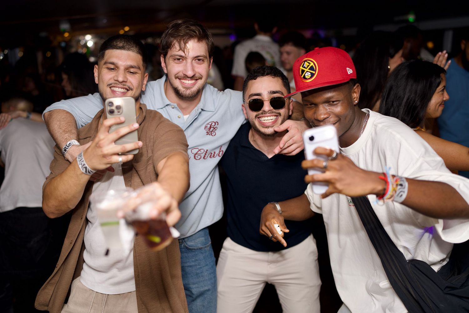 A group of guys leaning in close, laughing and posing for a front-facing selfie on the boat.