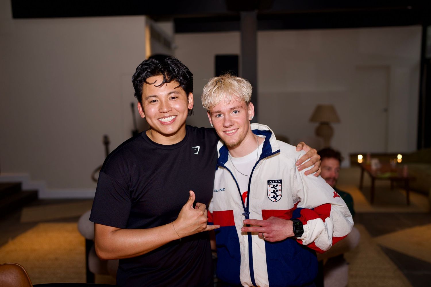 Two young men smiling together inside an event venue space during a fitness community social. Captured by ARIETA Studios.