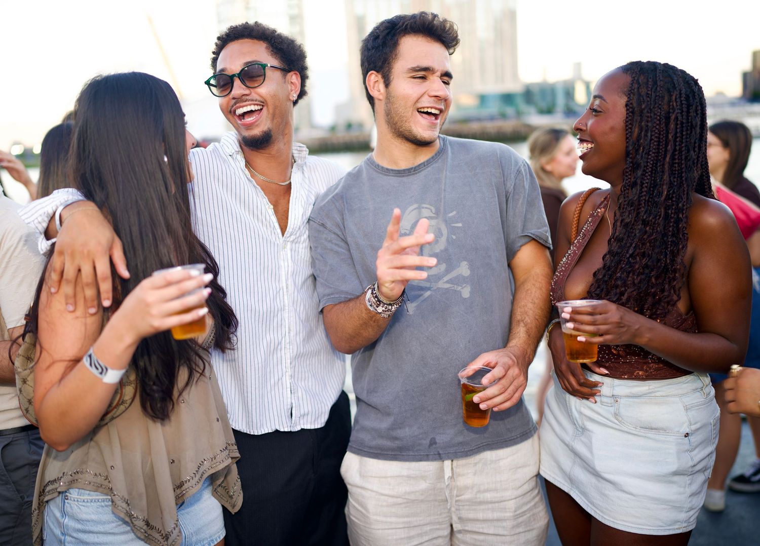 Friends laughing together with drinks on River Thames boat party by ARIETA Studios.