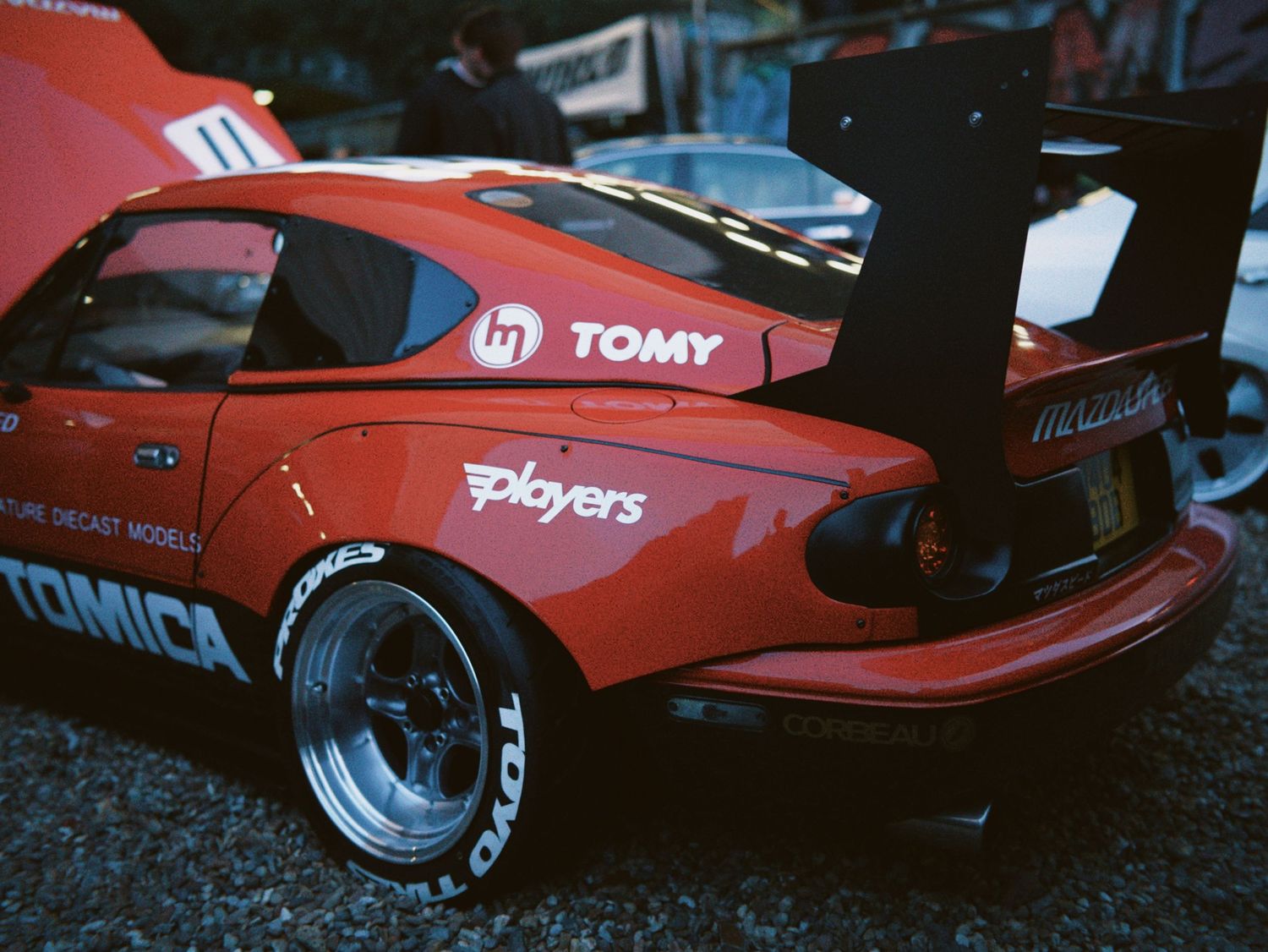 Rear view of a red Mazda MX-5 Miata track car with a massive GT wing and Tomica livery.