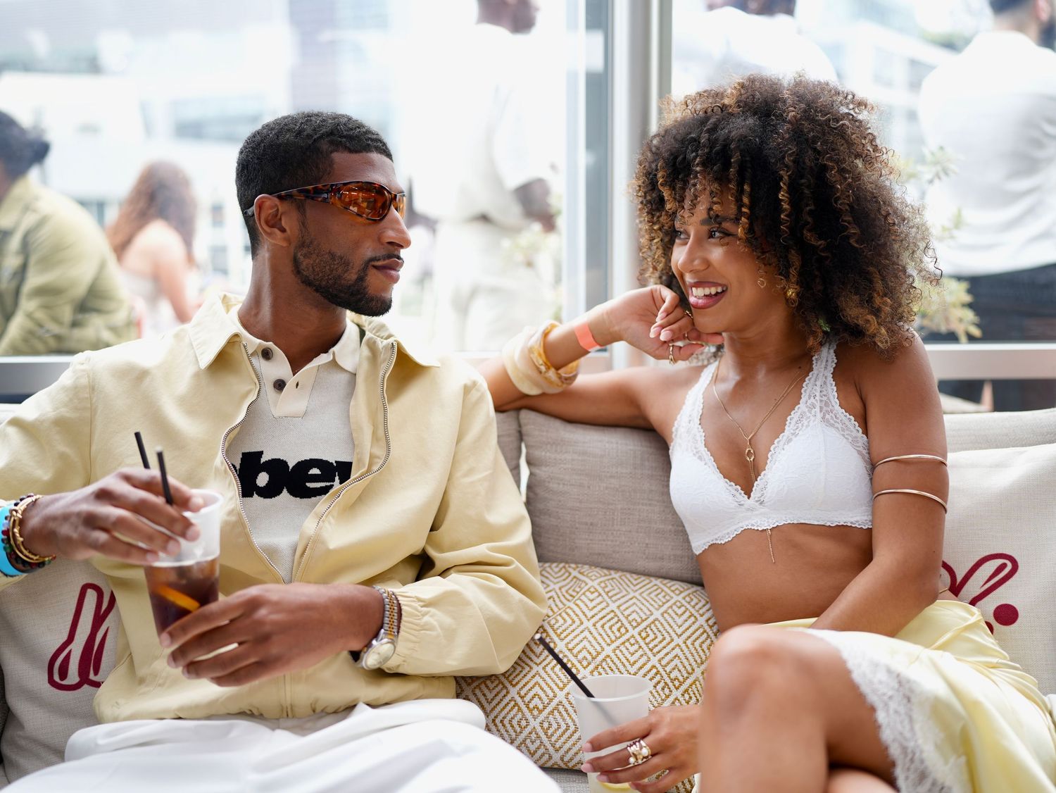 Candid shot of a man and woman smiling and interacting on a lounge couch at an outdoor event.