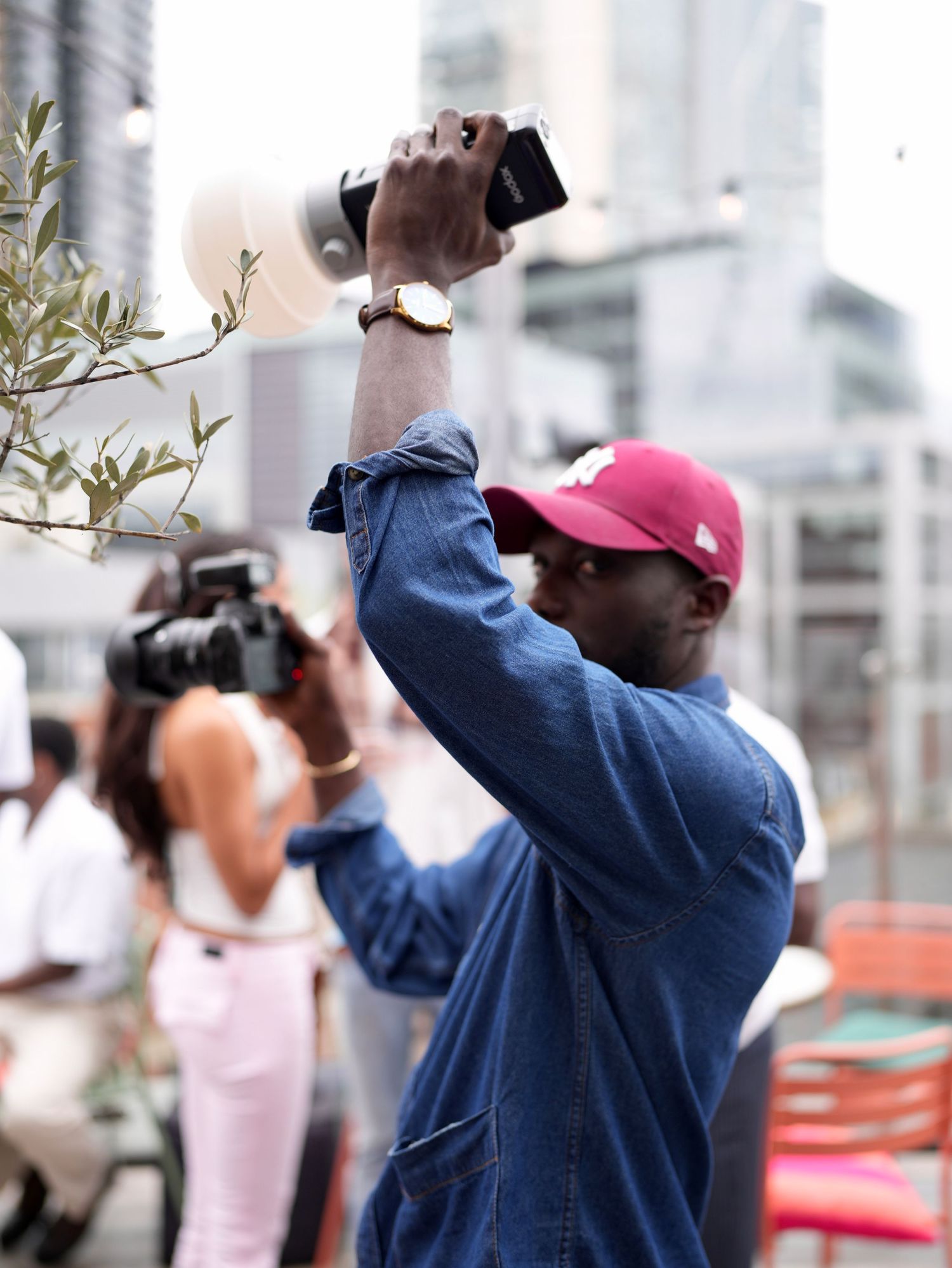 A crew member holding a portable flash diffuser high up to direct lighting at an outdoor production.