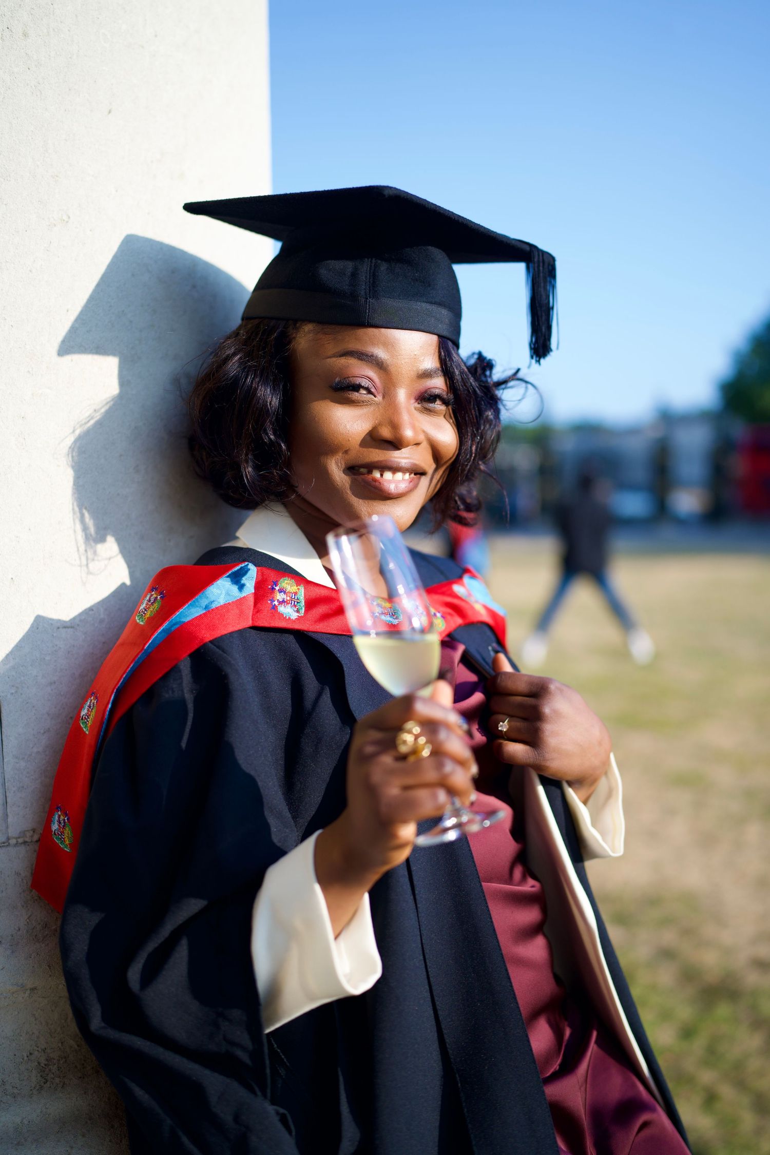 Smiling graduate holding a champagne glass at Old Royal Naval College photoshoot by ARIETA Studios.