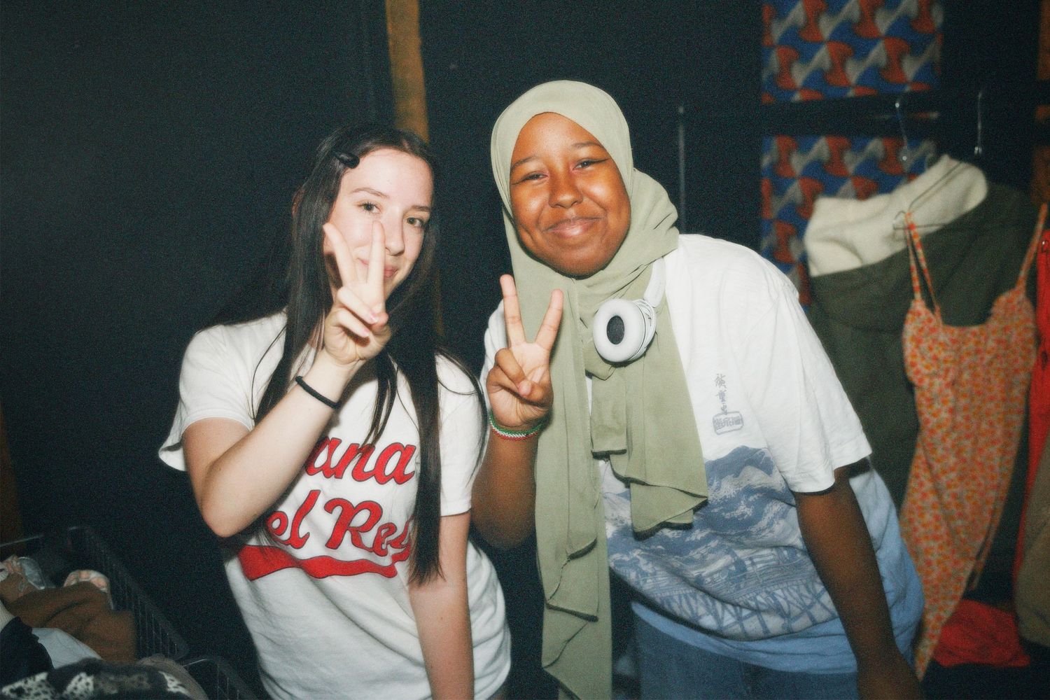 Two volunteers making peace signs and smiling warmly together during the Fashion For Future clothing exchange