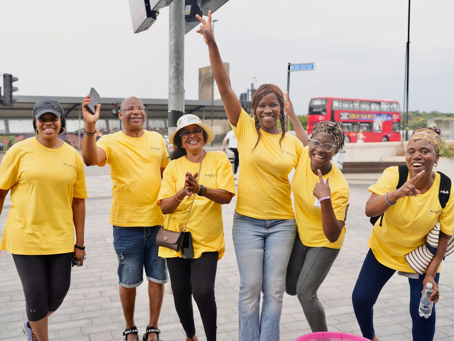 Volunteers in yellow shirts smiling and cheering during Streams of Joy Erith community outreach by ARIETA Studios