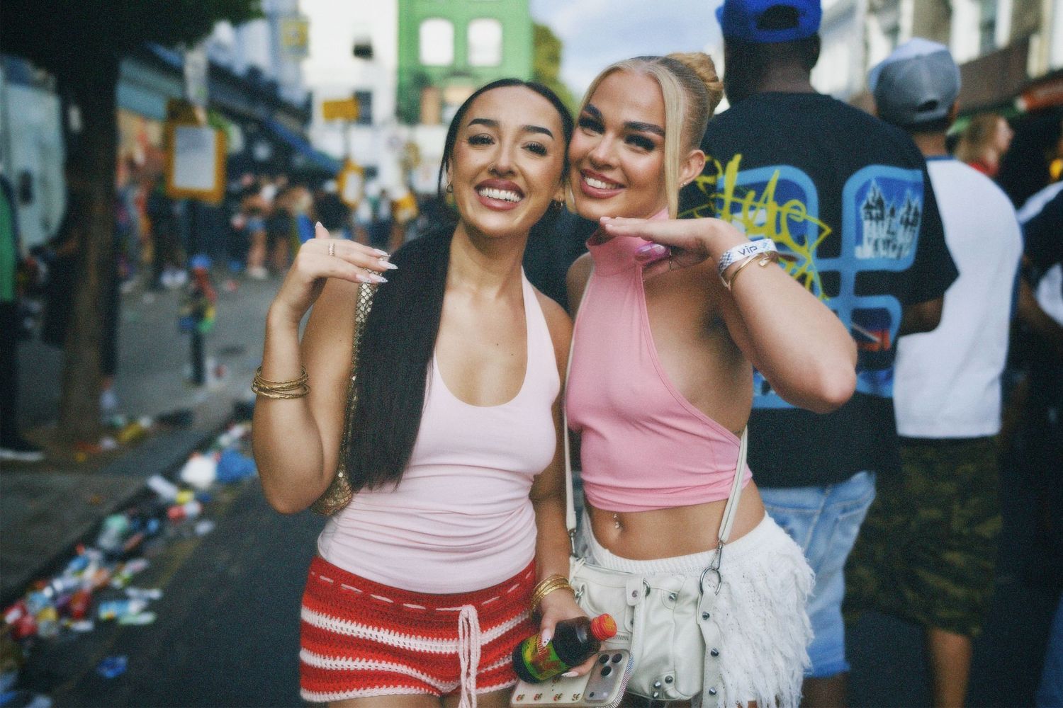 Two women smiling in co-ord festival tops while moving through the Carnival crowds.