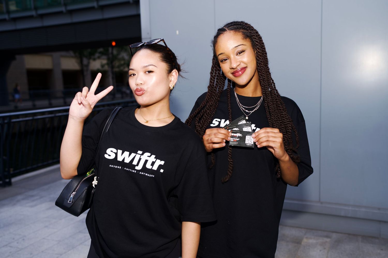 Two women in swiftr tees posing with peace sign and event pass captured by ARIETA Studios.