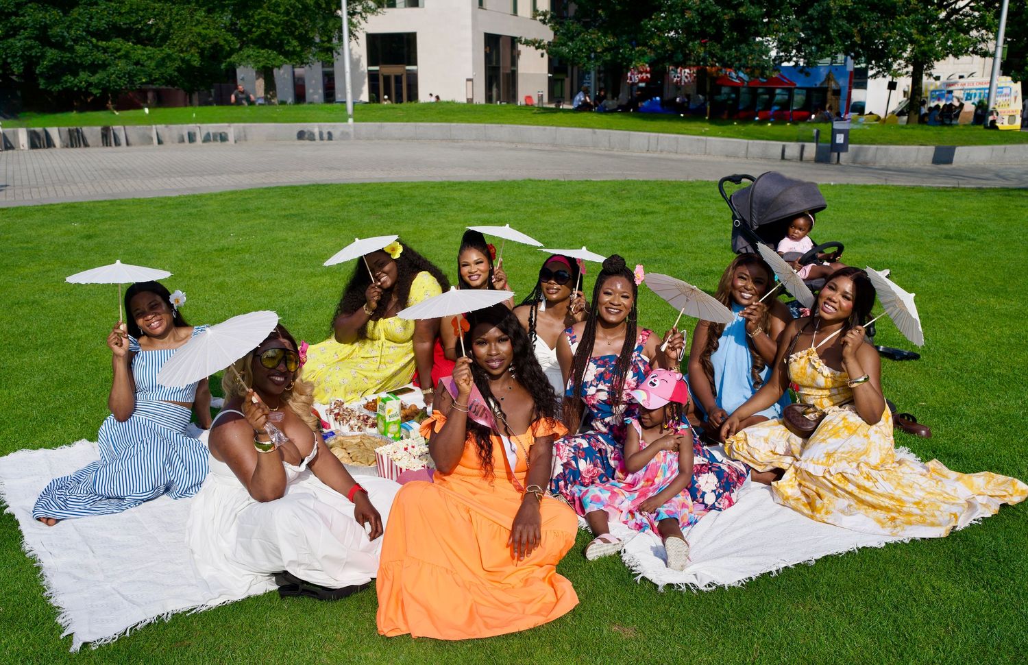 Group of women lounging on picnic blanket during outdoor celebration by ARIETA Studios.