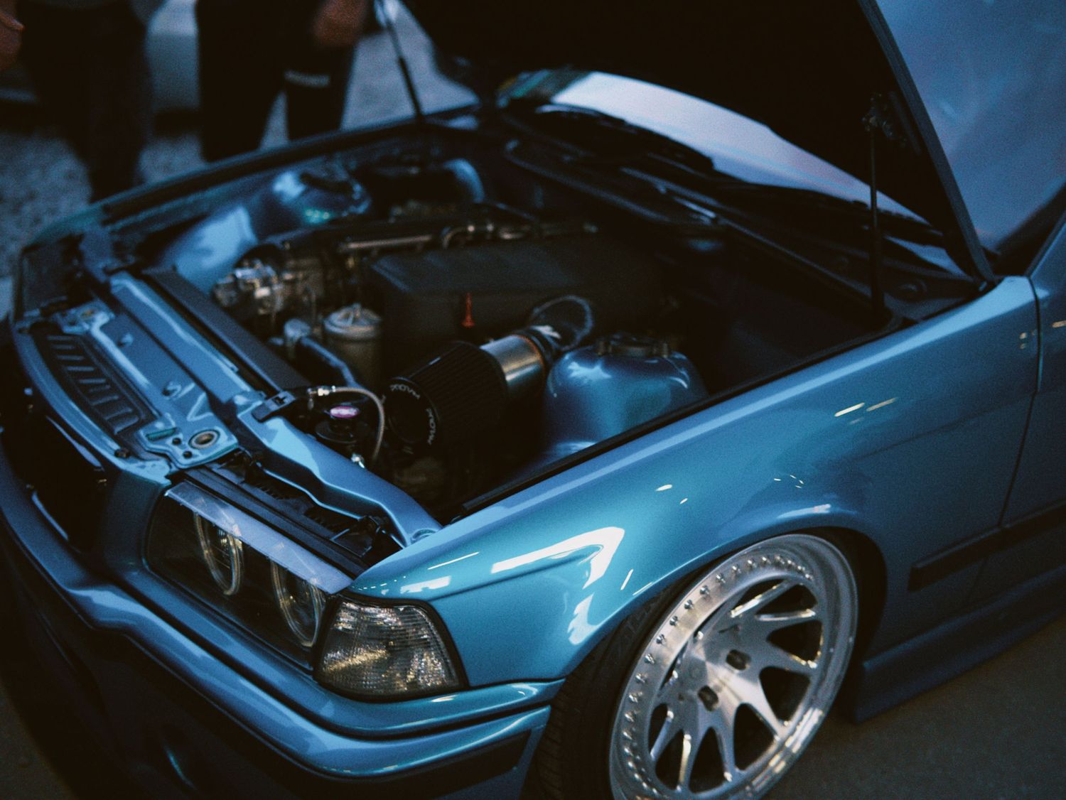Close-up of modified metallic blue car engine bay by ARIETA Studios.