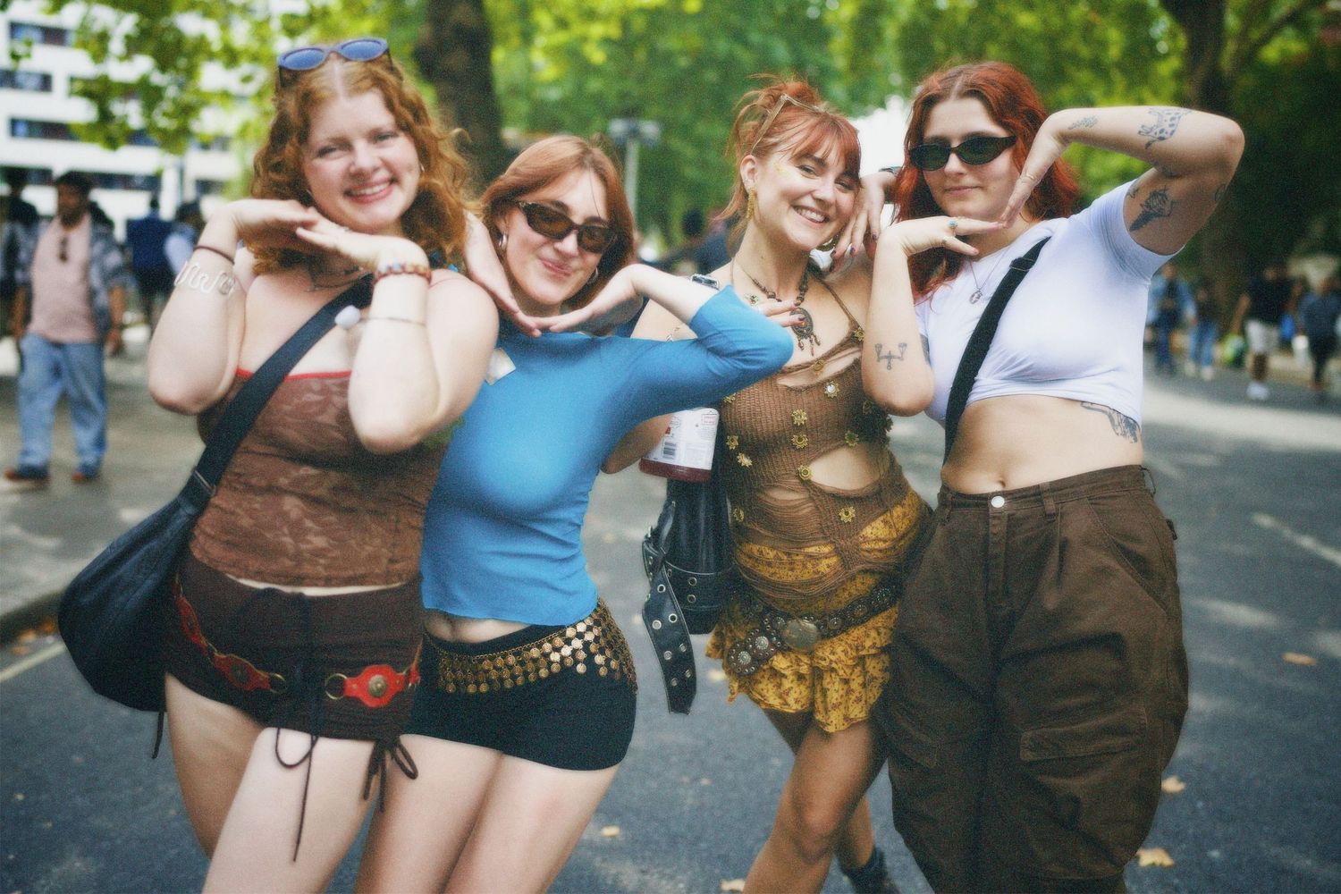 Four friends lined up across the street holding signature poses in colourful festival outfits.