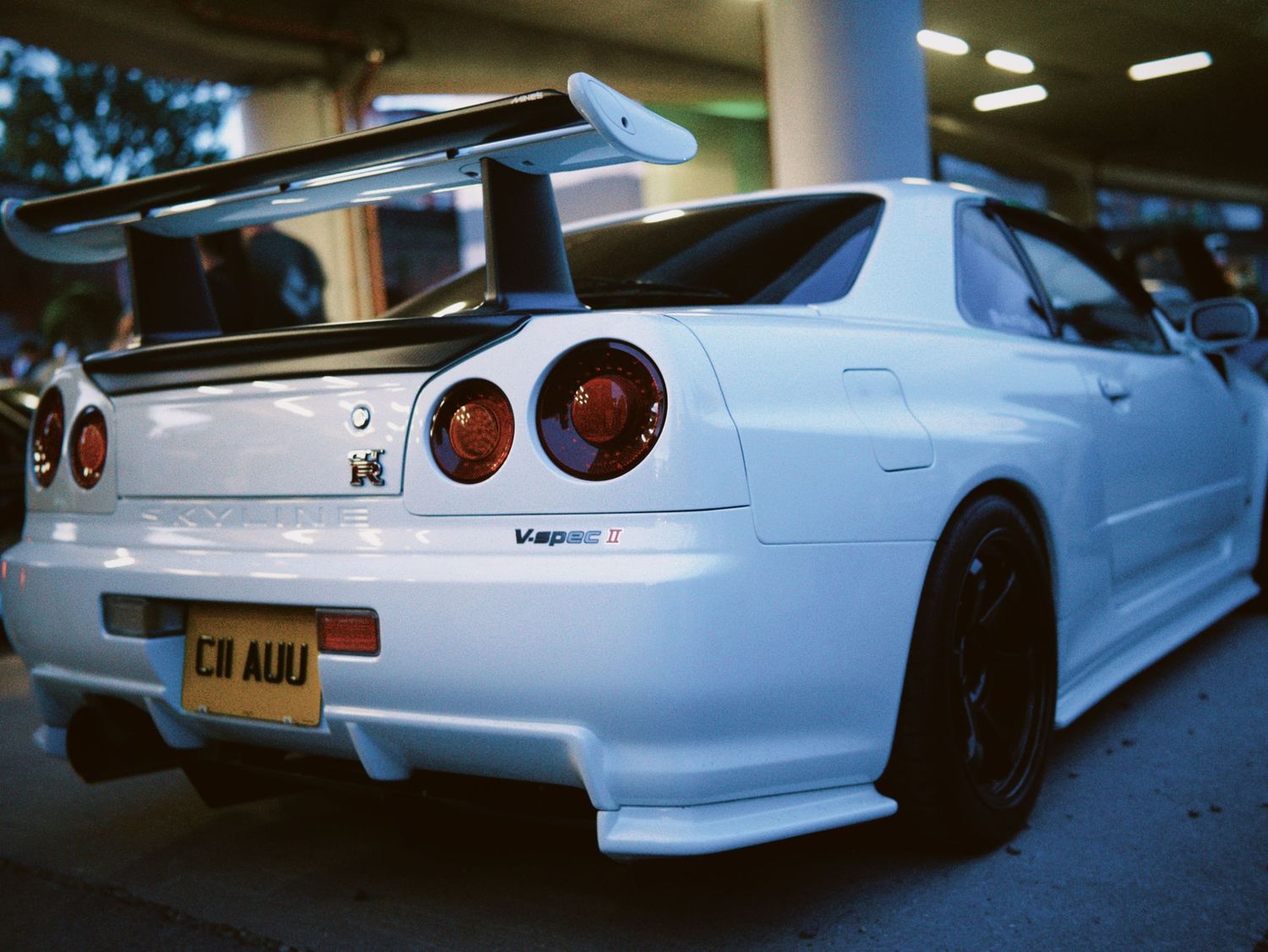 Rear view of custom white Nissan Skyline GT-R R34 sports car by ARIETA Studios.