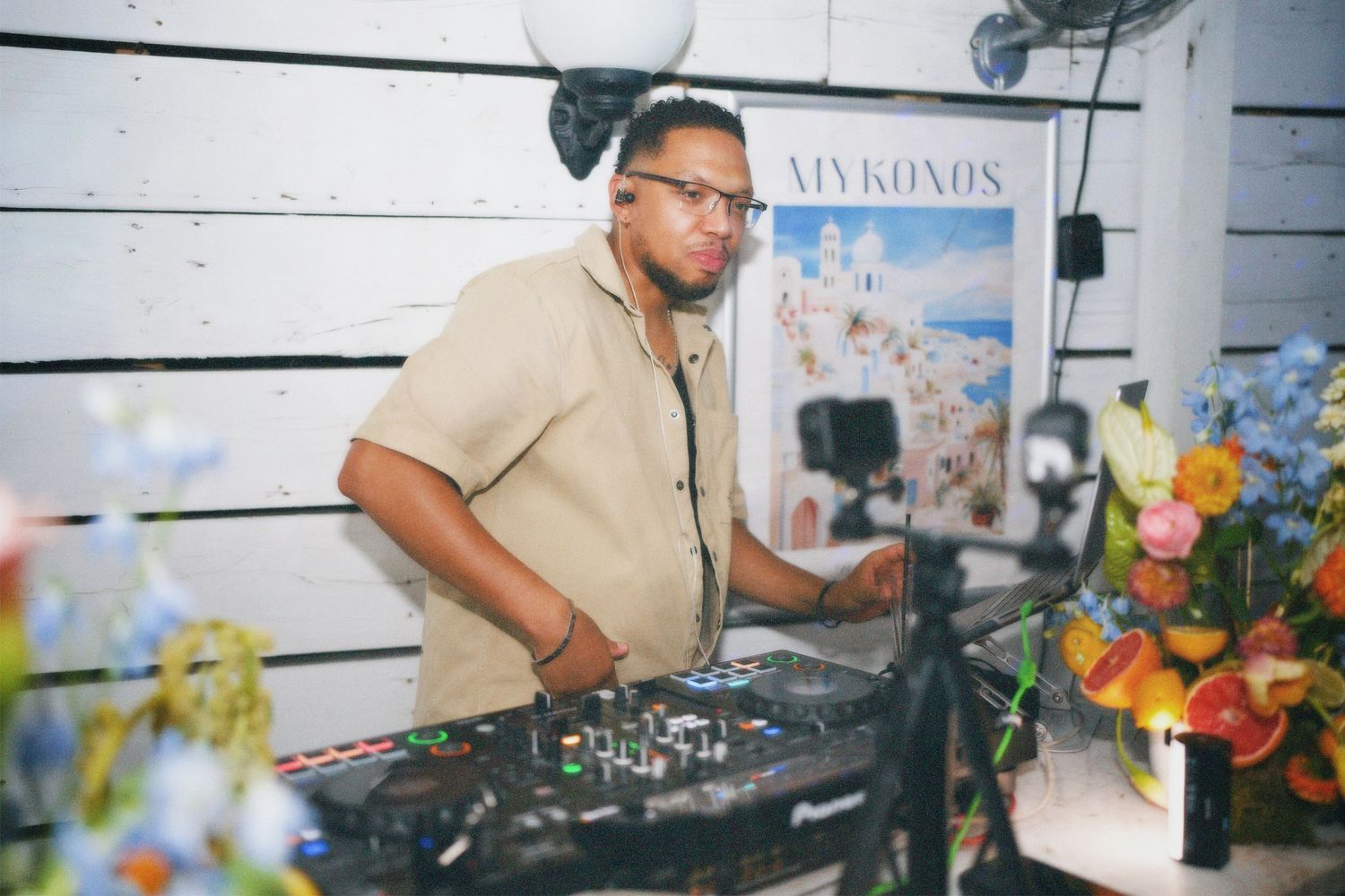 DJ mixing music behind DJ equipment at a bright daytime event.
