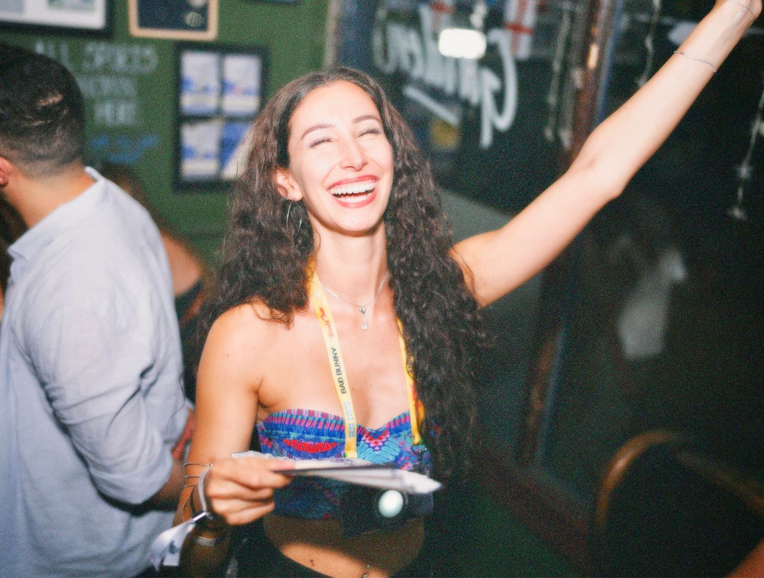 Woman laughing with arm raised on lively dancefloor by ARIETA Studios.