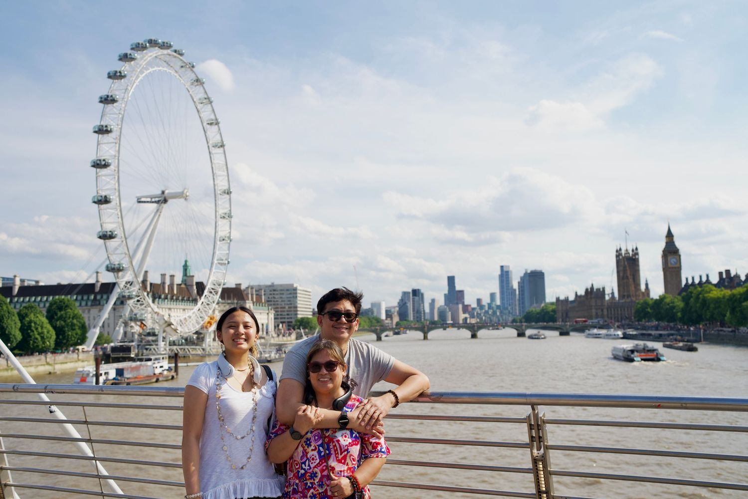 Couple posing together along River Thames with London Eye behind them by ARIETA Studios.