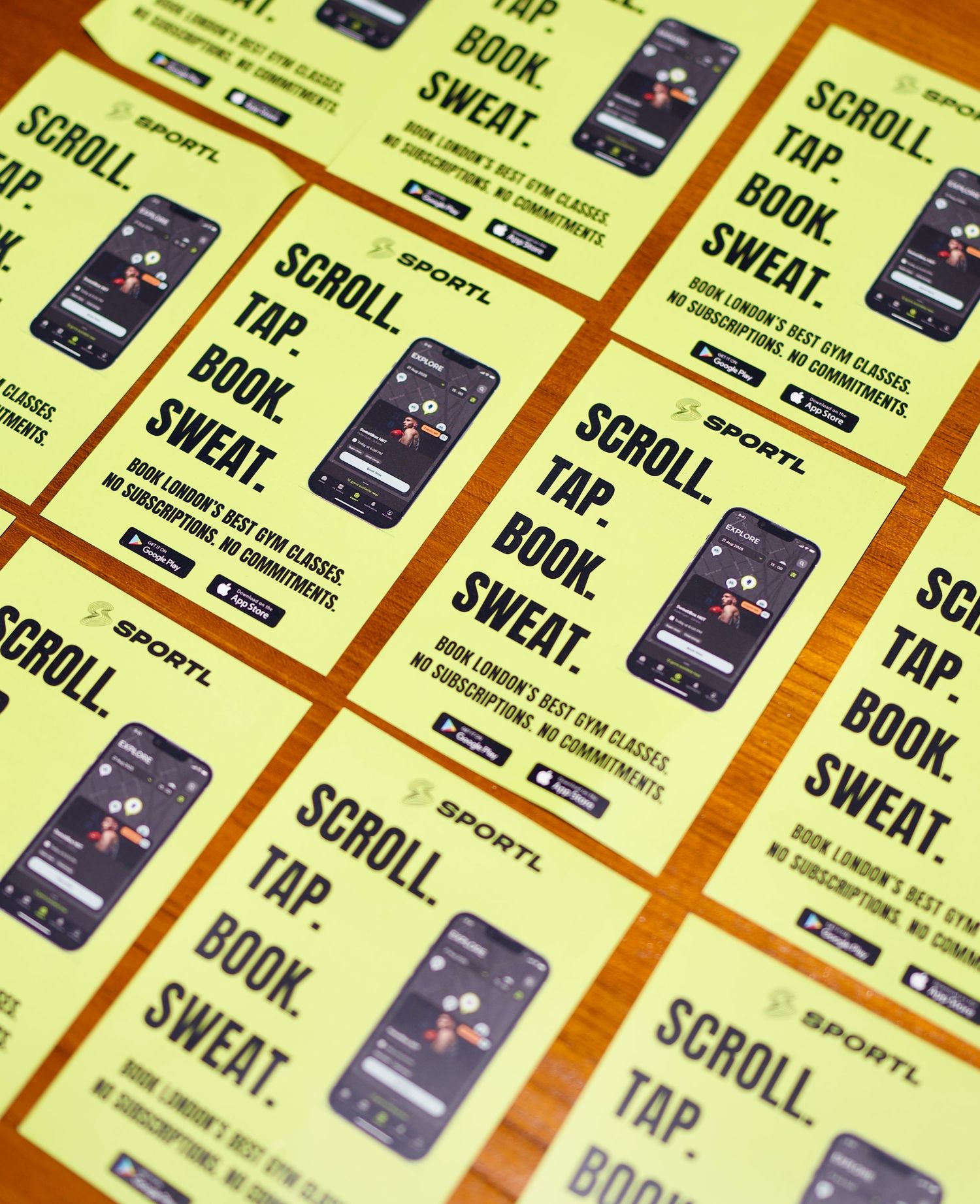 Macro shot of lime green SPORTL promotional flyers displaying the mobile app interface and download links. Photo by ARIETA Studios.