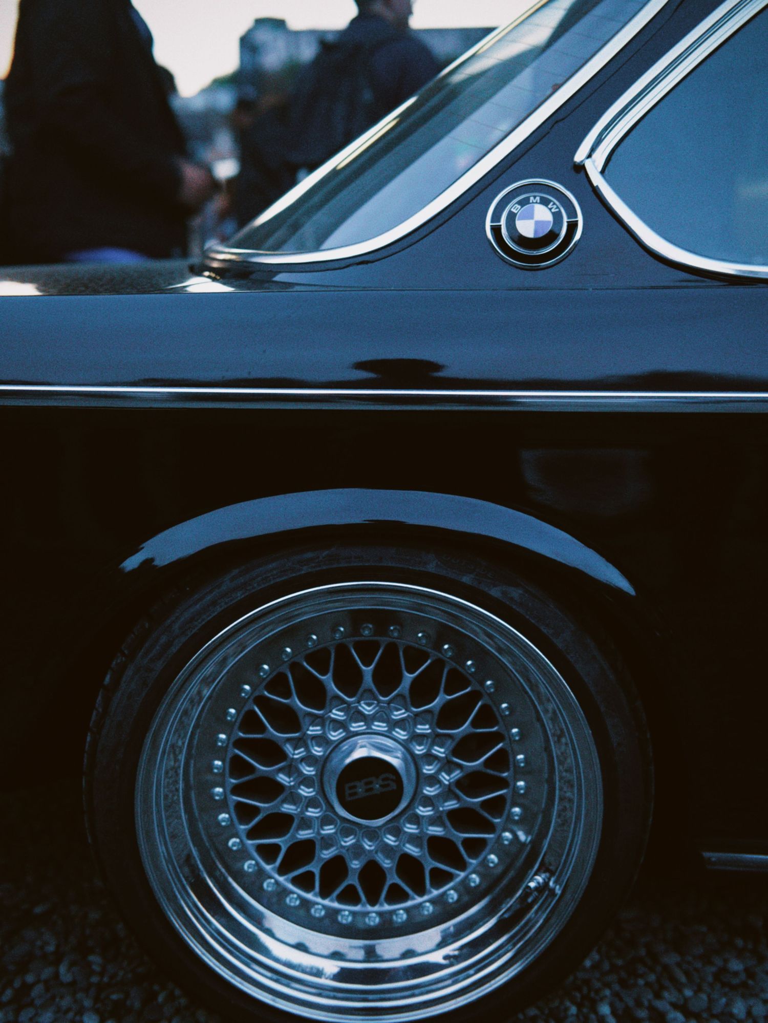 Close-up shot of a classic wire spoke wheel rim and tire tread on a vintage vehicle.