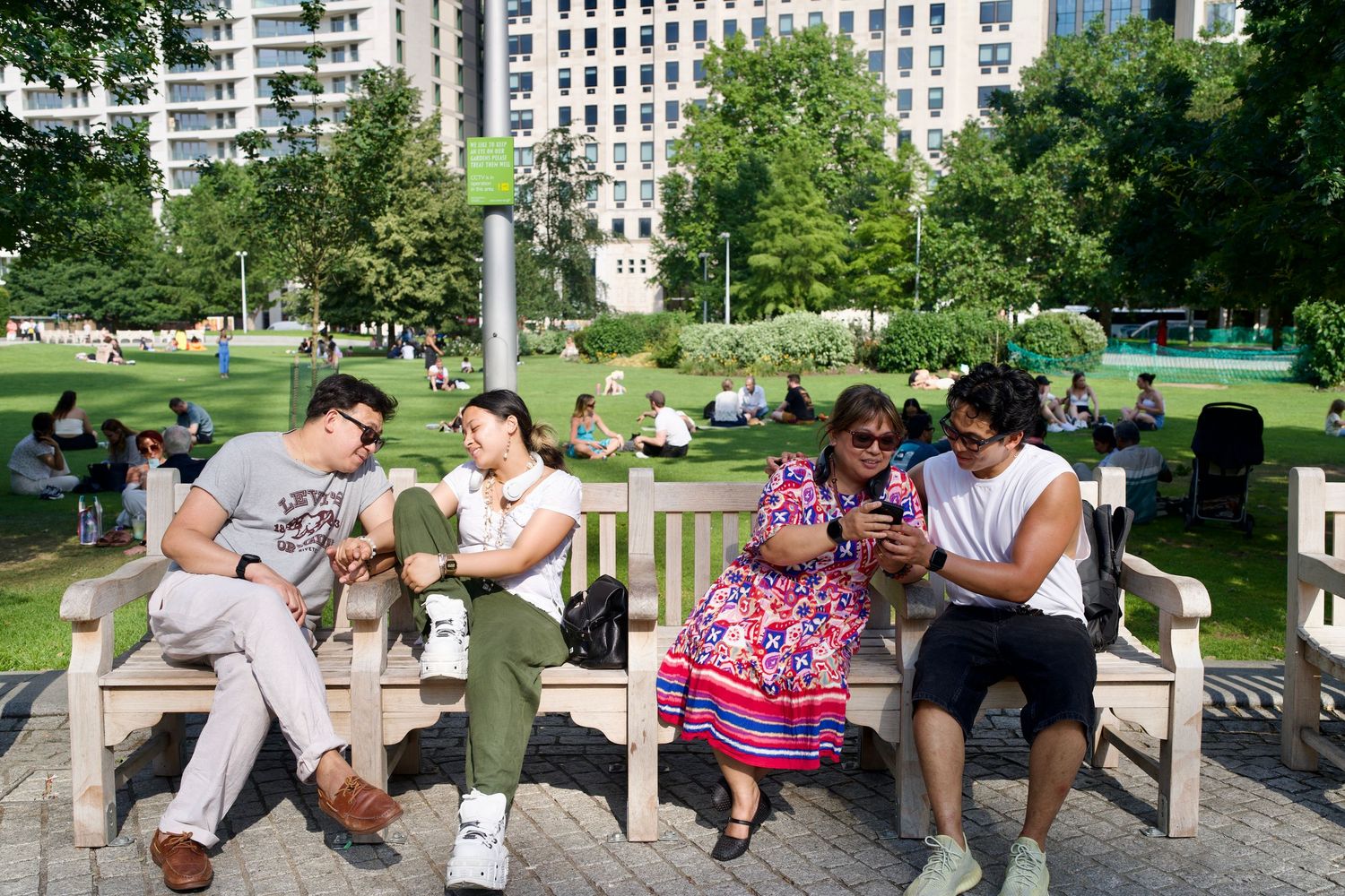 Two candid street photos of a family interacting and flashing peace signs on a wooden park bench in a London square.