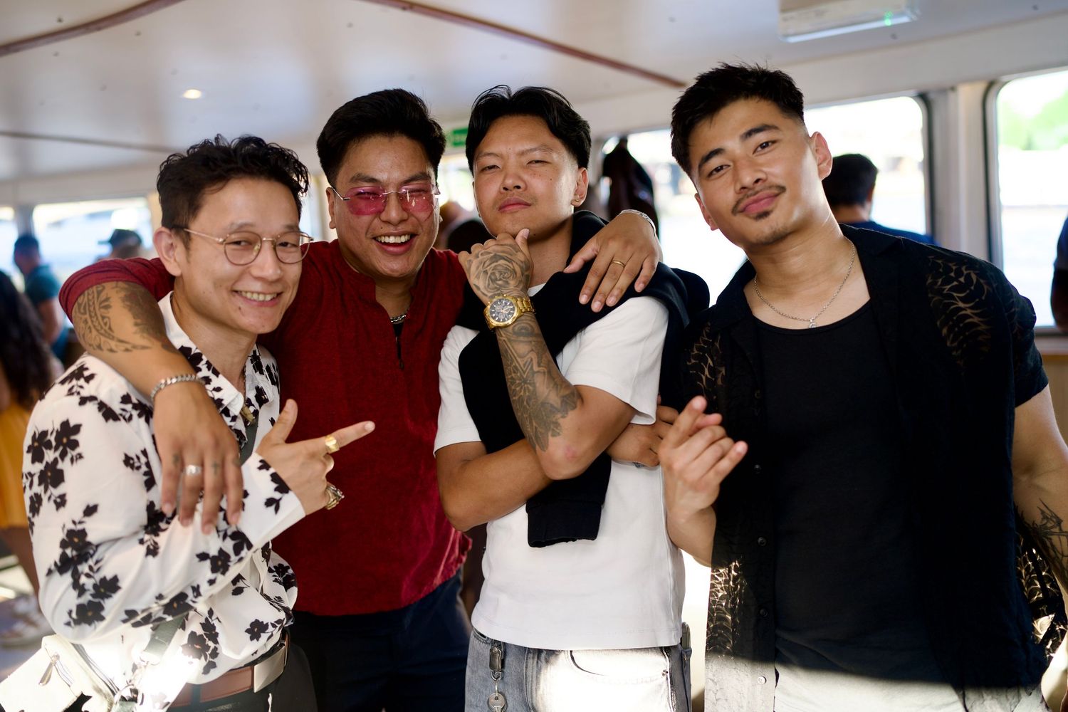 Four friends smiling and embracing, enjoying the upbeat energy during a daytime river cruise event.