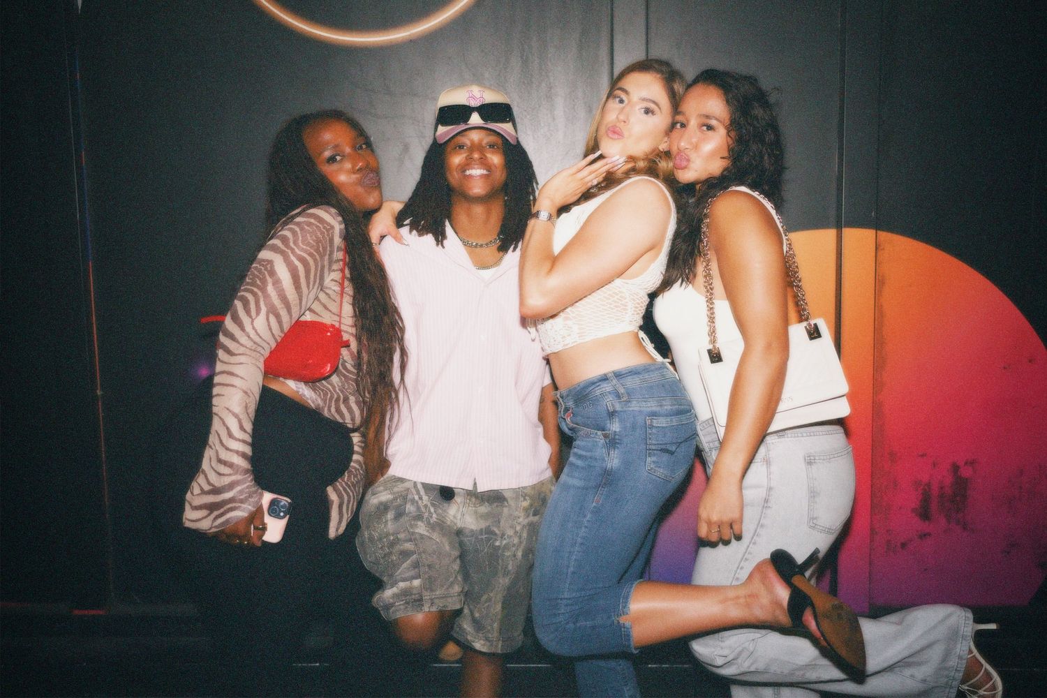 Three women posing and laughing together at an energetic nightlife event.