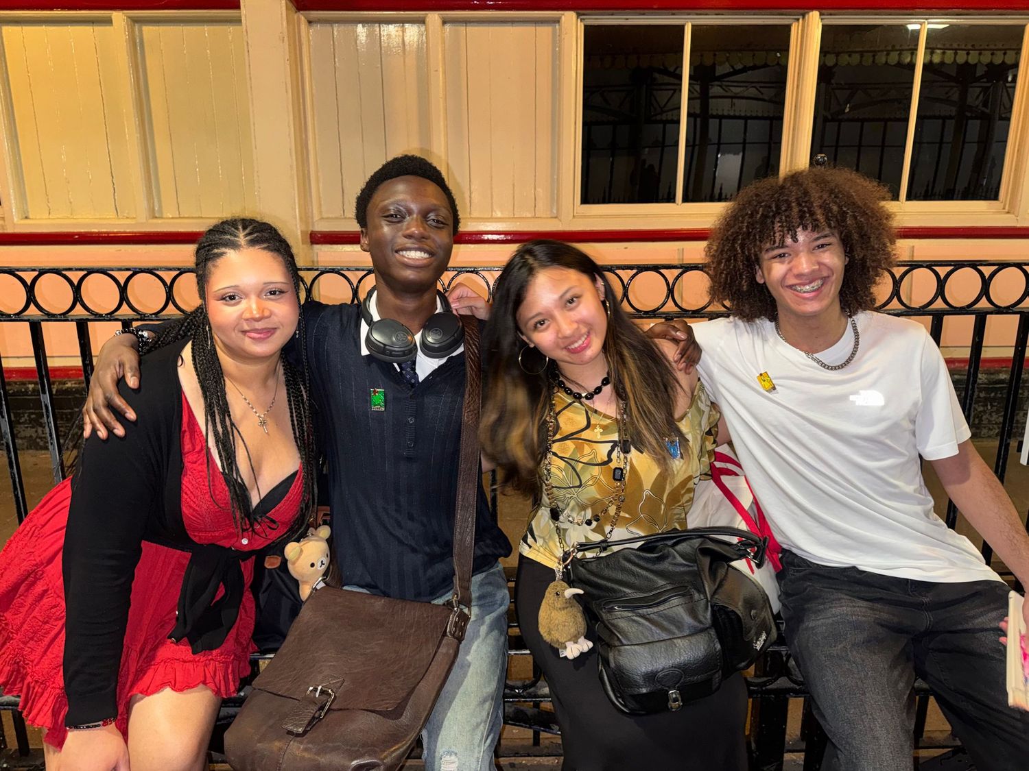 The crew smiling together along a platform railing at the train station.