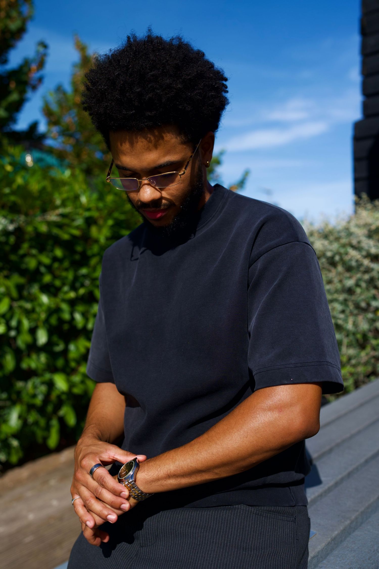 Casual outdoor portrait of a Habeeb, a model, sitting on stone steps in natural daylight.