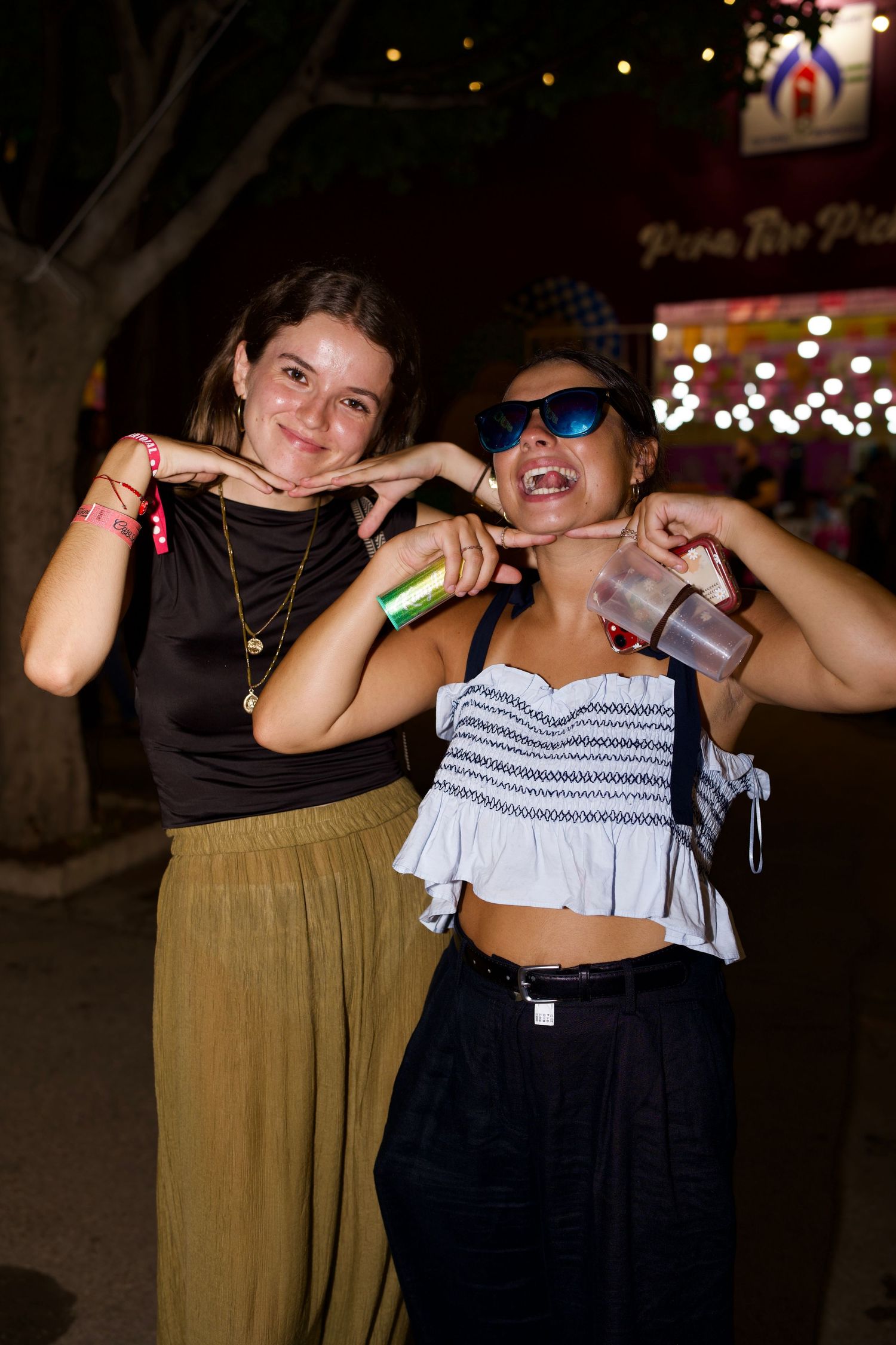 Two women smiling playfully at Feria / Dos mujeres posando sonrientes en la Feria de Málaga.