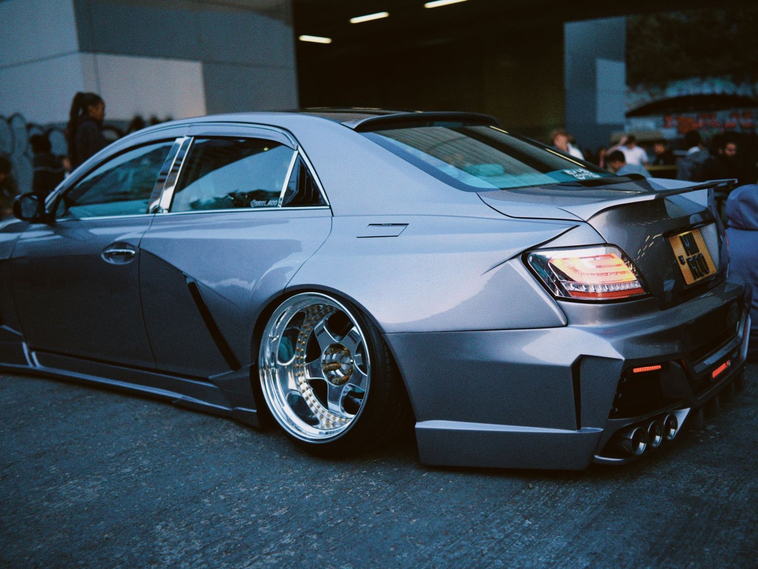 Custom grey Mercedes-Benz saloon with a widebody kit and deep dish chrome wheels.