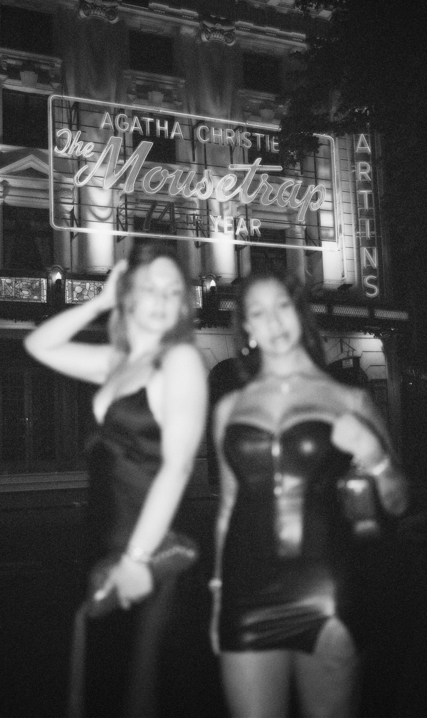 Black and white shot of friends dancing with hands in the air at club by ARIETA Studios.