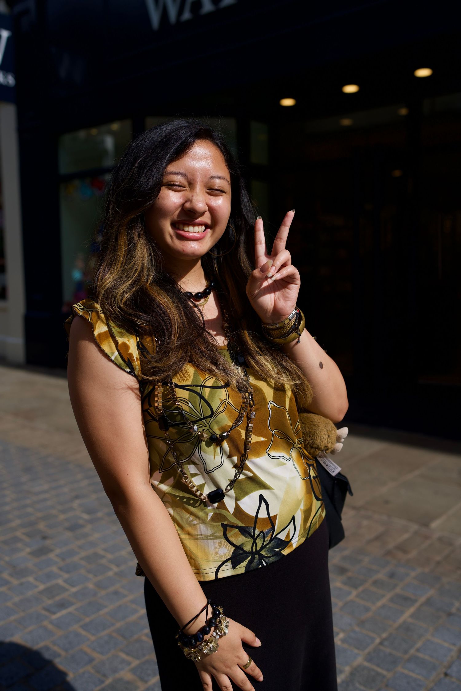 Teen girl laughing and throwing up a peace sign in natural sunlight.