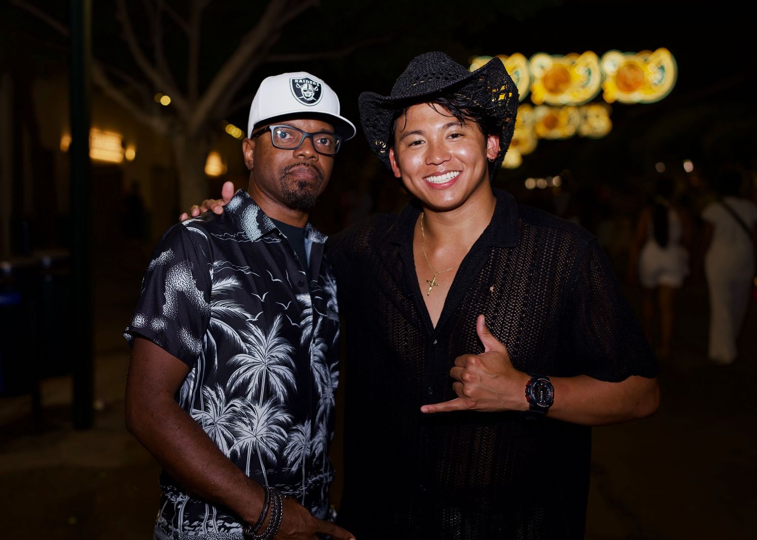 Two men smiling under night fair lights / Dos hombres sonriendo bajo las luces del Real.
