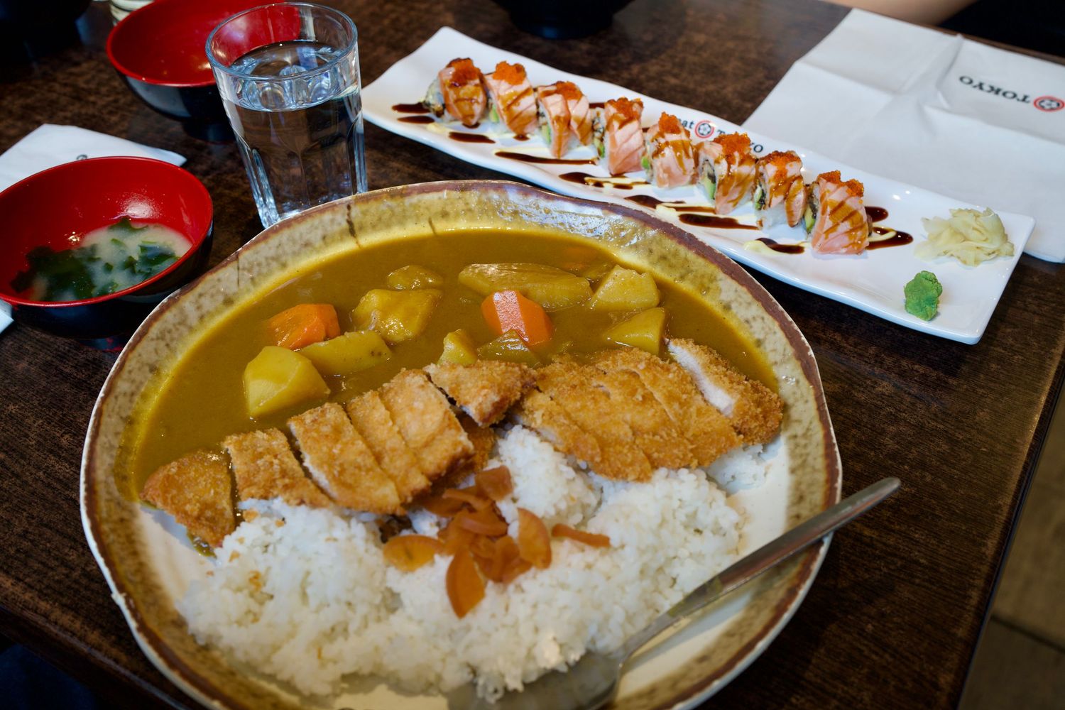 Japanese curry bowl with rice and side dishes served family-style across an ambient dining table.